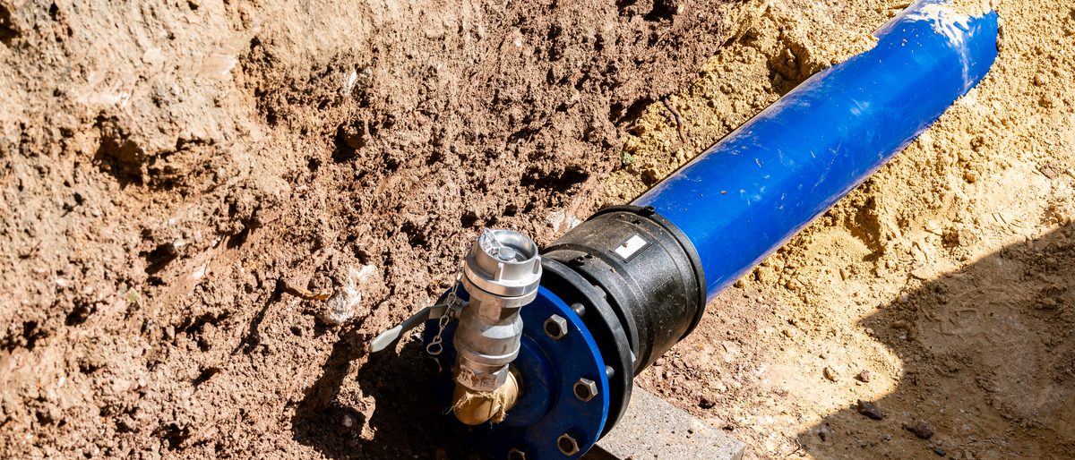 Blue water supply pipe joined to a valve in an open trench