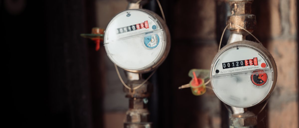 Two older water meters attached to pipework on a wall
